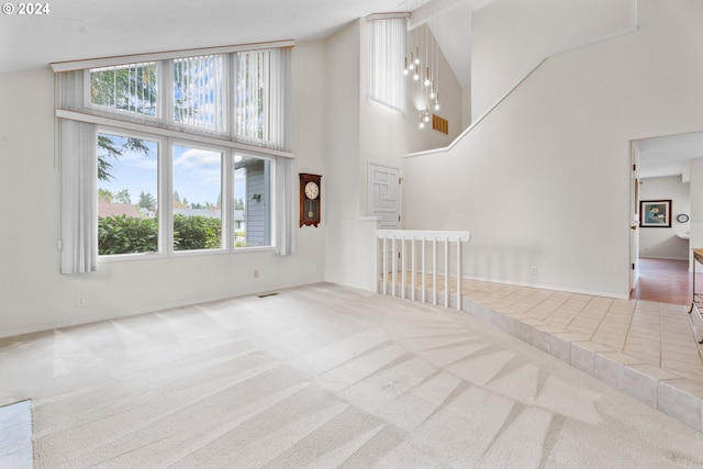 unfurnished living room with carpet, a towering ceiling, and plenty of natural light