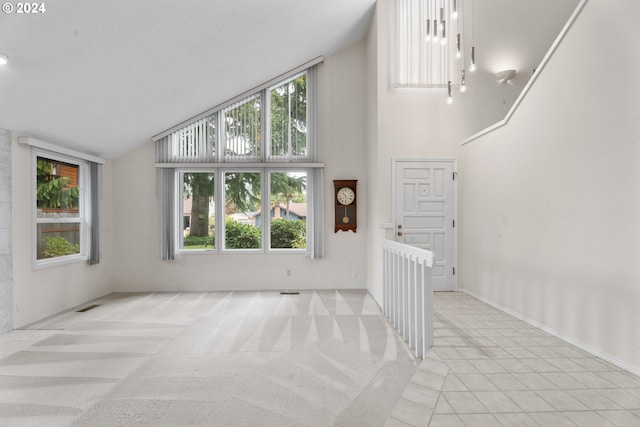 unfurnished living room with light colored carpet and high vaulted ceiling