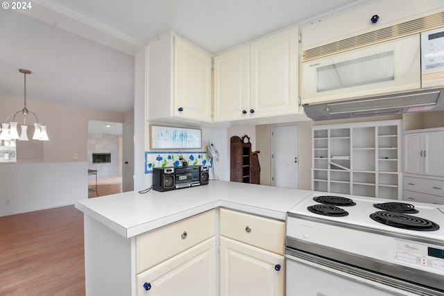 kitchen featuring kitchen peninsula, a fireplace, electric stove, white cabinets, and hanging light fixtures