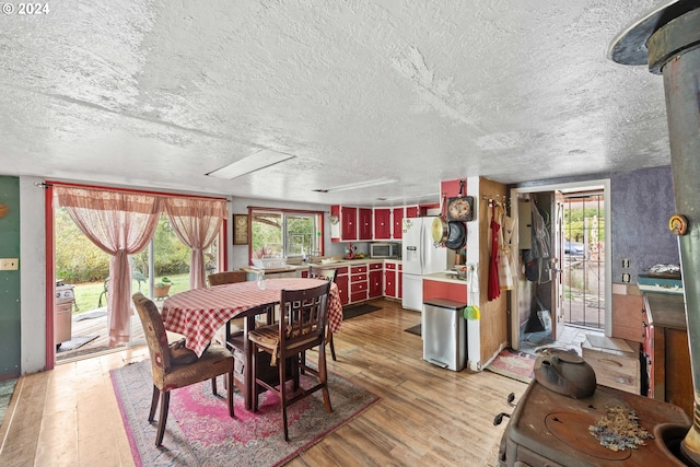 dining room with a textured ceiling, light wood finished floors, and a healthy amount of sunlight