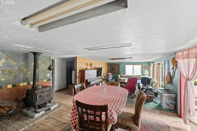 dining space with a wood stove, a textured ceiling, and wood finished floors