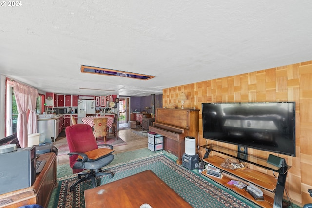 living room with hardwood / wood-style floors, a textured ceiling, wooden walls, and plenty of natural light