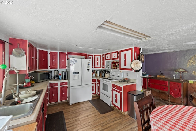 kitchen featuring white appliances, a textured ceiling, dark wood-type flooring, and sink