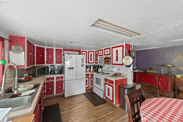 kitchen with a sink, a textured ceiling, white appliances, and light countertops