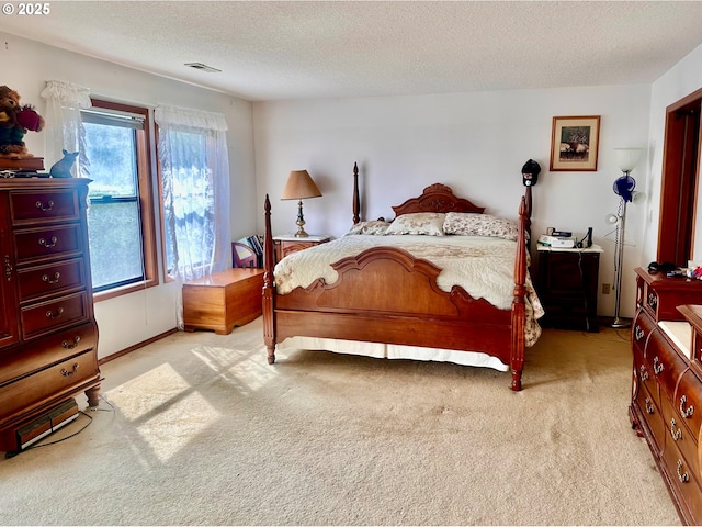 bedroom featuring light colored carpet, visible vents, and a textured ceiling