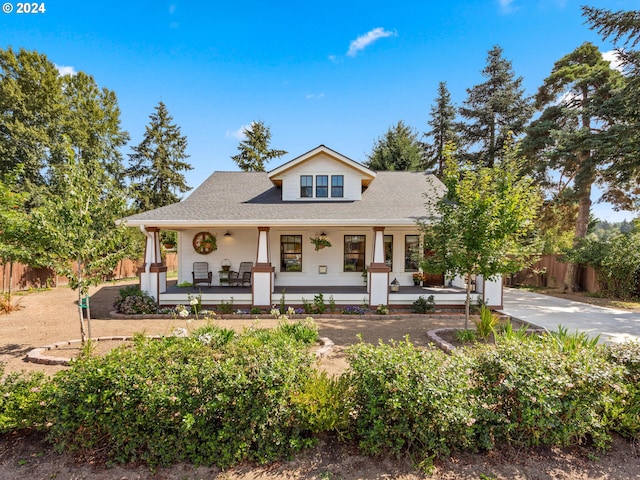 view of front of property with fence, covered porch, driveway, and roof with shingles