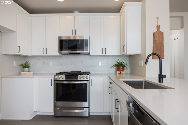 kitchen with dark hardwood / wood-style flooring, white cabinets, sink, and stainless steel appliances