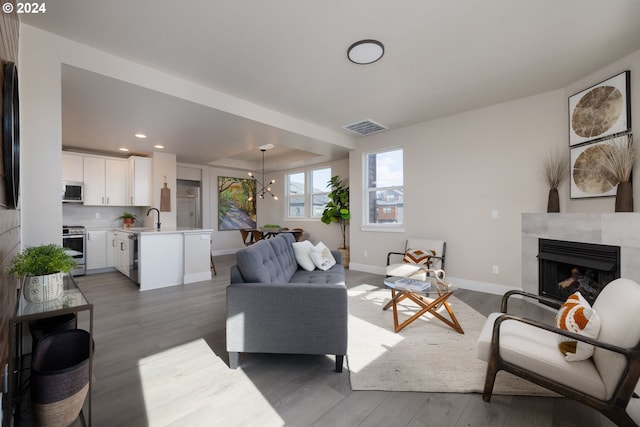 living room with dark hardwood / wood-style floors, sink, and a notable chandelier