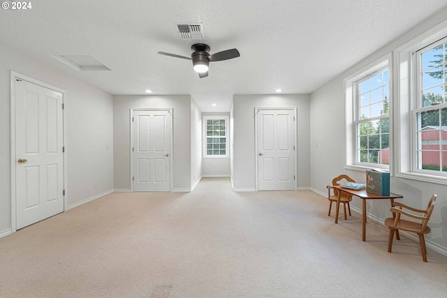 sitting room with a textured ceiling, ceiling fan, and light carpet