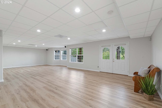 unfurnished living room featuring light hardwood / wood-style flooring, french doors, and a drop ceiling