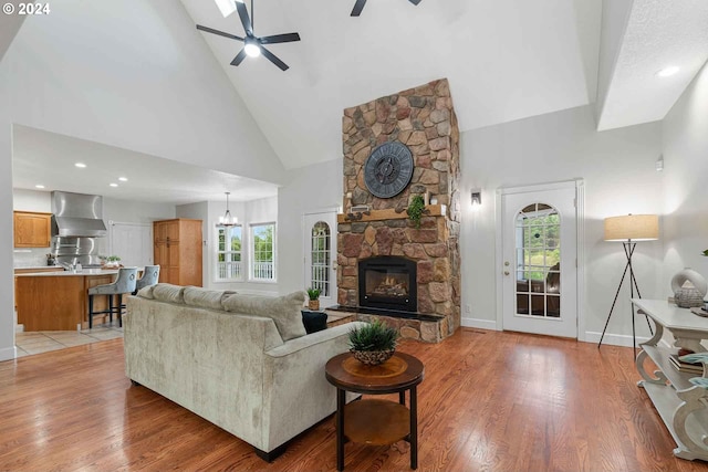 living room featuring ceiling fan with notable chandelier, plenty of natural light, high vaulted ceiling, and a fireplace