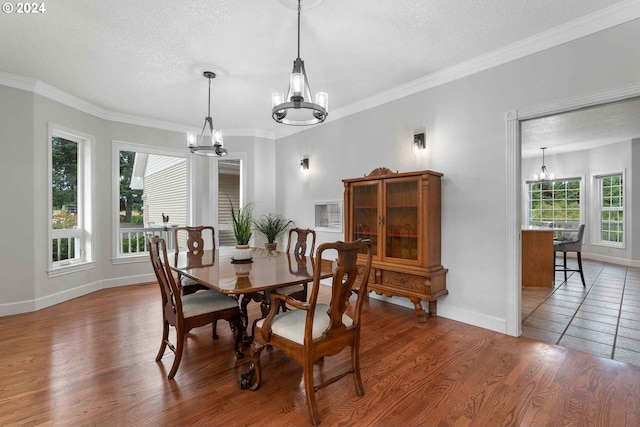 dining space with a notable chandelier, a textured ceiling, ornamental molding, and wood-type flooring