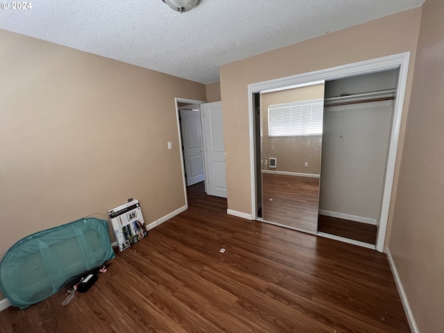 unfurnished bedroom with a closet, a textured ceiling, and dark hardwood / wood-style flooring