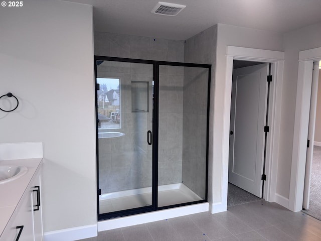 bathroom featuring tile patterned flooring, an enclosed shower, and vanity