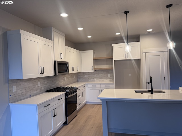 kitchen featuring white cabinetry, appliances with stainless steel finishes, decorative backsplash, pendant lighting, and sink