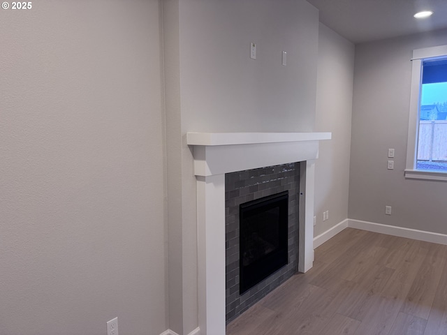 room details featuring wood-type flooring and a tiled fireplace