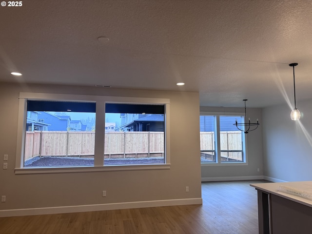 unfurnished room with a textured ceiling, hardwood / wood-style flooring, and a notable chandelier