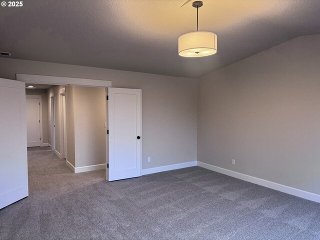 carpeted spare room featuring a textured ceiling and vaulted ceiling