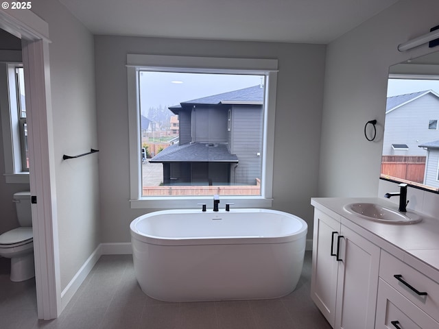 bathroom with a bath, toilet, plenty of natural light, and vanity