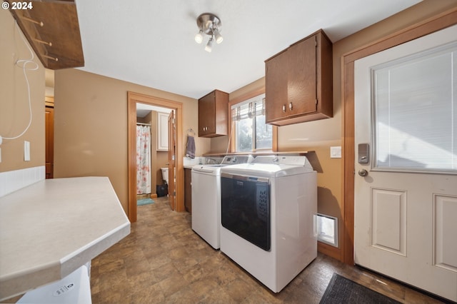 washroom featuring washing machine and clothes dryer and cabinets