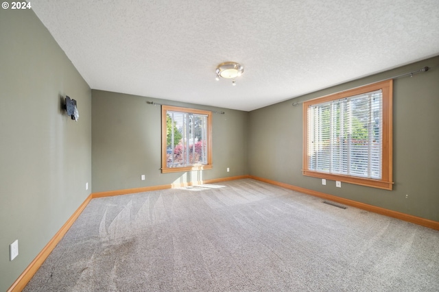 carpeted empty room with a textured ceiling