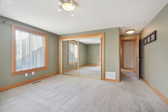 unfurnished bedroom with light carpet, a closet, and a textured ceiling