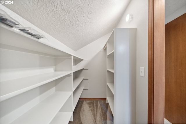 spacious closet featuring lofted ceiling and dark carpet