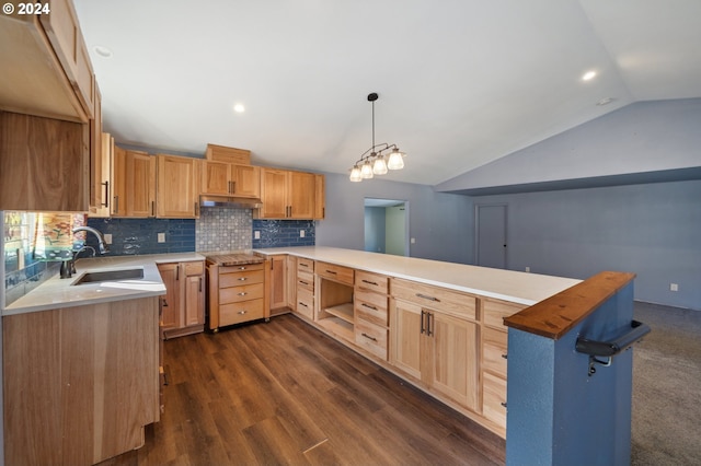 kitchen with dark wood-type flooring, kitchen peninsula, sink, vaulted ceiling, and pendant lighting