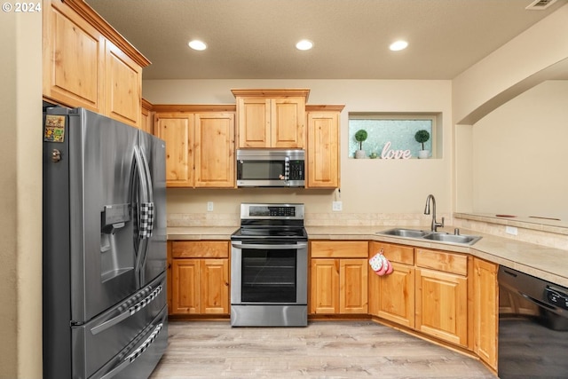 kitchen with sink, stainless steel appliances, and light hardwood / wood-style floors