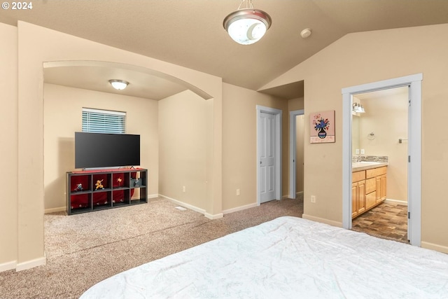 bedroom featuring carpet floors, vaulted ceiling, and ensuite bath