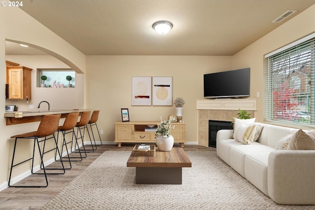 living room featuring a textured ceiling, a fireplace, and light hardwood / wood-style flooring