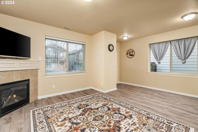 unfurnished living room featuring a fireplace, wood-type flooring, and a textured ceiling