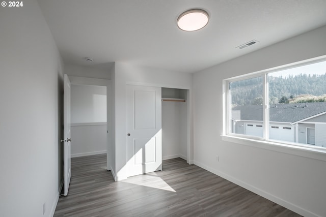 unfurnished bedroom featuring dark hardwood / wood-style flooring and a closet