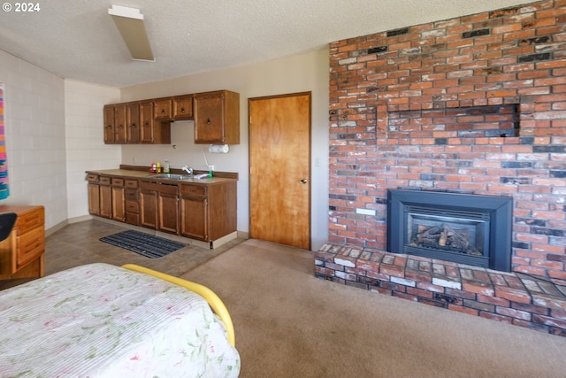 kitchen featuring a fireplace, a textured ceiling, light colored carpet, and sink