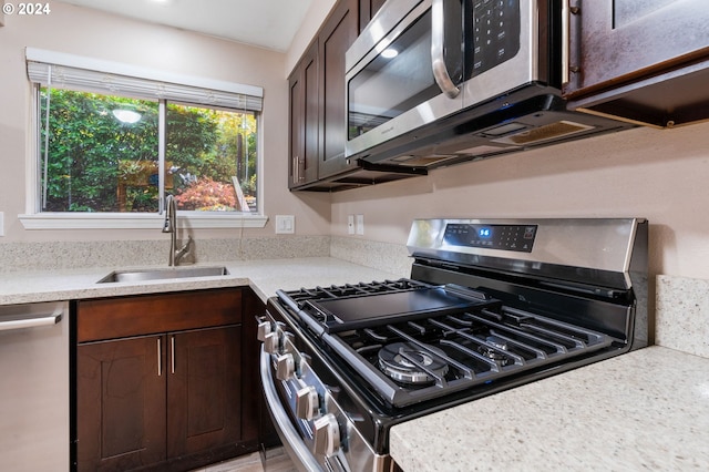 kitchen with dark brown cabinetry, stainless steel appliances, and sink