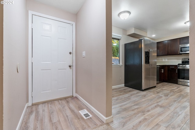 kitchen with dark brown cabinets, stainless steel appliances, and light hardwood / wood-style flooring