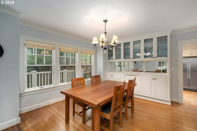 dining room with light wood-type flooring, an inviting chandelier, and ornamental molding