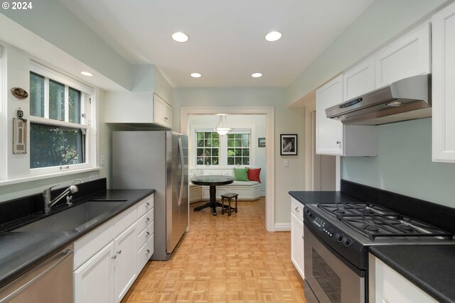 kitchen with sink, stainless steel appliances, light parquet flooring, and white cabinets