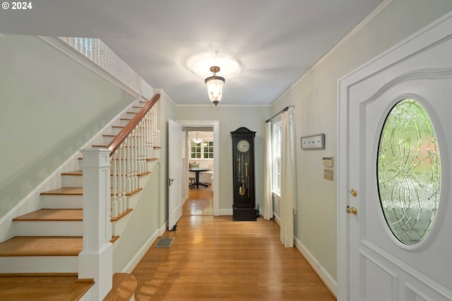 foyer entrance with light wood-type flooring and crown molding