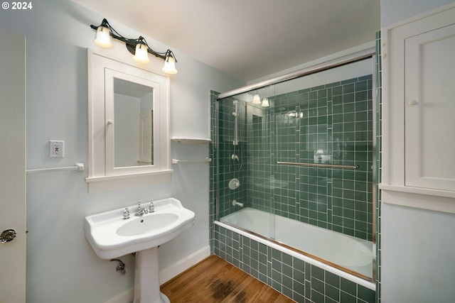 bathroom with hardwood / wood-style floors and bath / shower combo with glass door