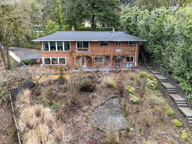 back of house featuring stairway, a chimney, and a deck