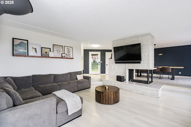 living room featuring a stone fireplace, a textured ceiling, and wood finished floors