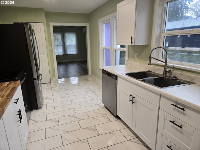 kitchen featuring white cabinetry, stainless steel appliances, sink, and light wood-type flooring