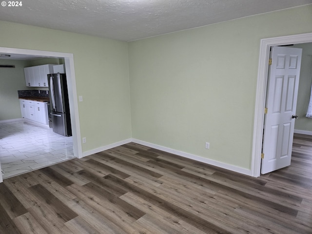 spare room with a textured ceiling and dark wood-type flooring