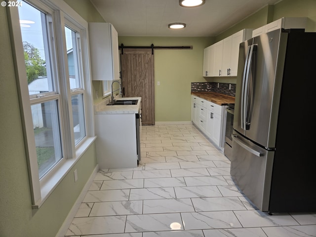 kitchen featuring sink, white cabinets, stainless steel appliances, and a barn door