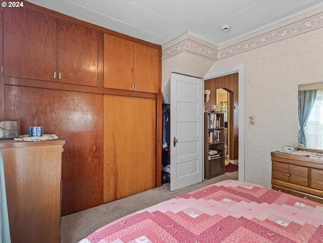 carpeted bedroom featuring wooden walls and ornamental molding