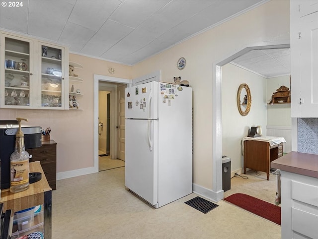 kitchen with white cabinets, white fridge, and crown molding