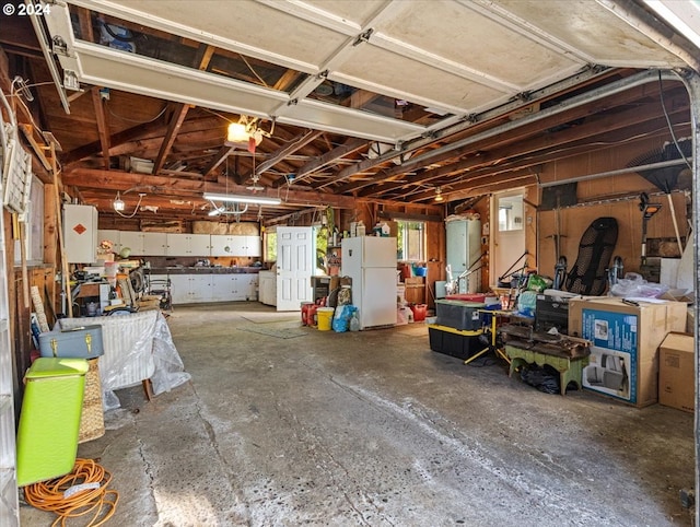 garage featuring stainless steel fridge, washer / dryer, and white fridge