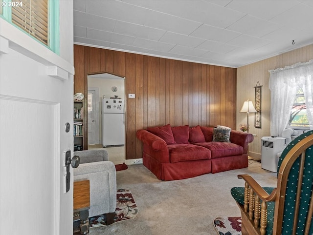 carpeted living room with ornamental molding and wooden walls