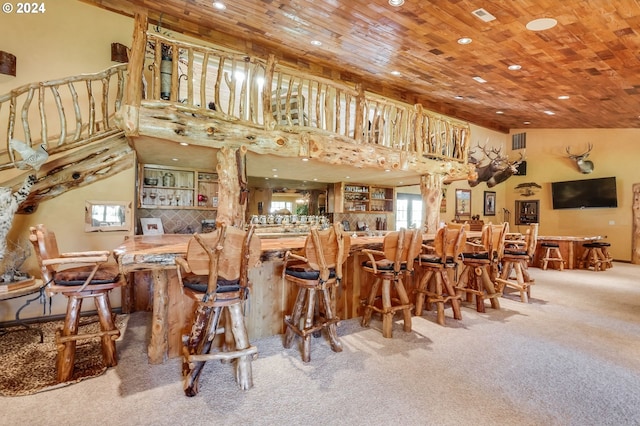 dining space with indoor bar, wooden ceiling, carpet floors, and a high ceiling